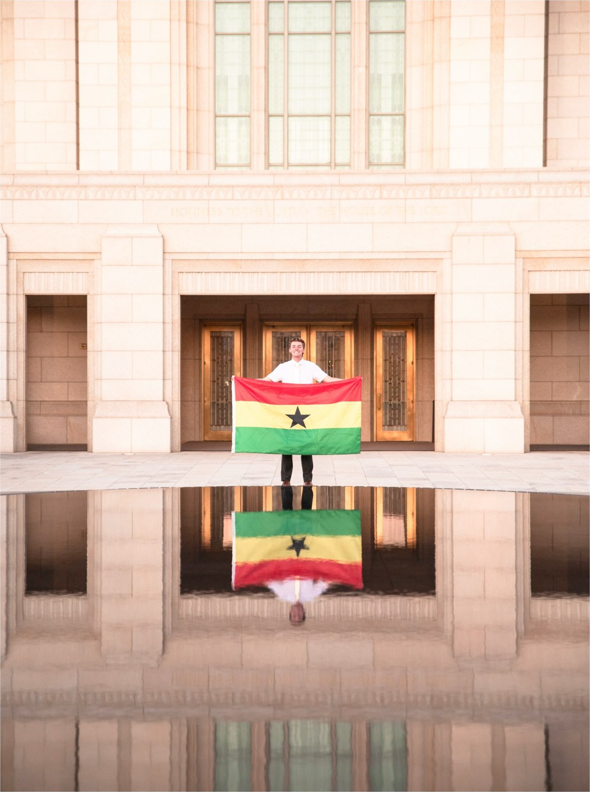 Elder Jonas Archibald holding the flag of Ghana in front of the temple